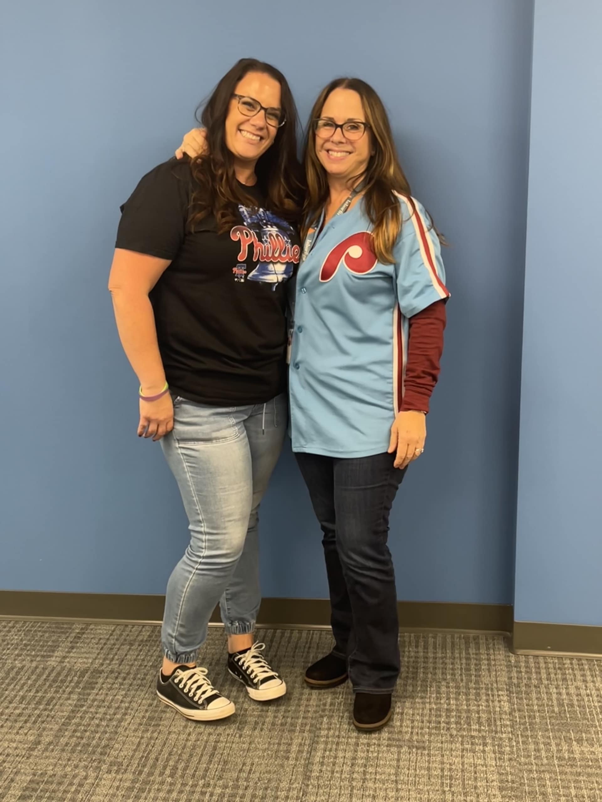 Two women wearing Phillies merchandise, smiling