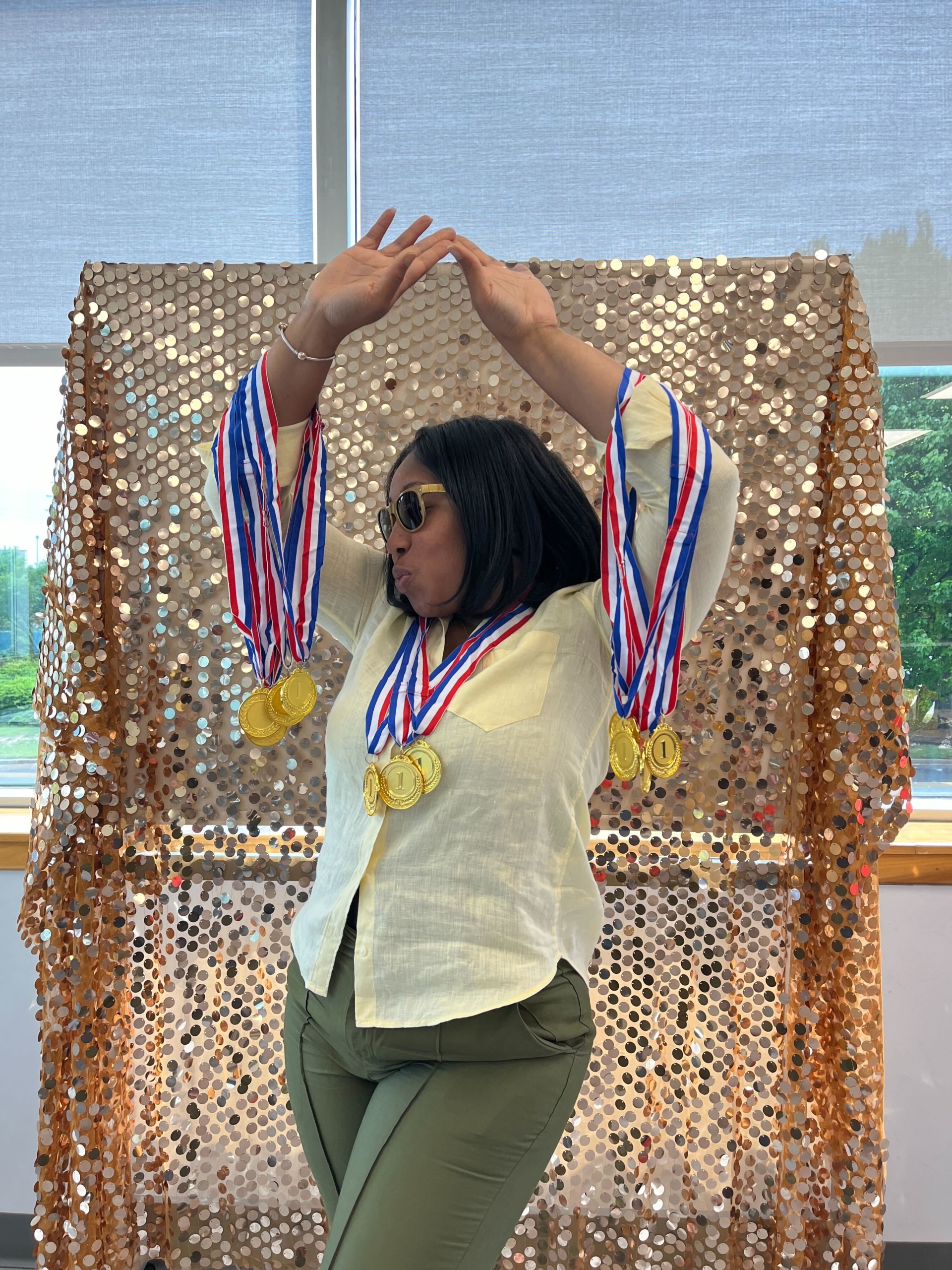 woman wearing many gold medal ribbons in front of a gold wall
