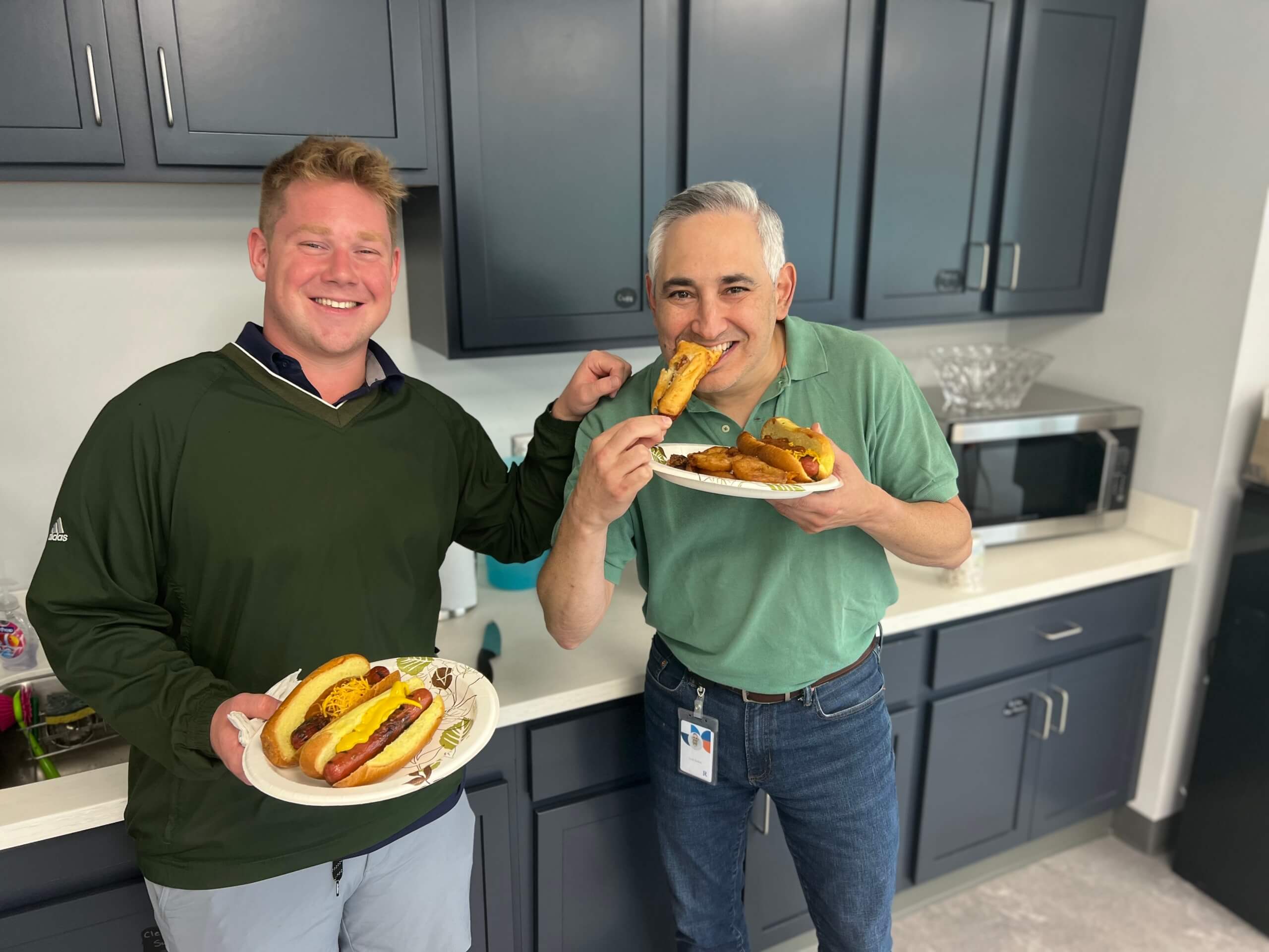 Two RetireeFirst employees posing with plate of hotdogs