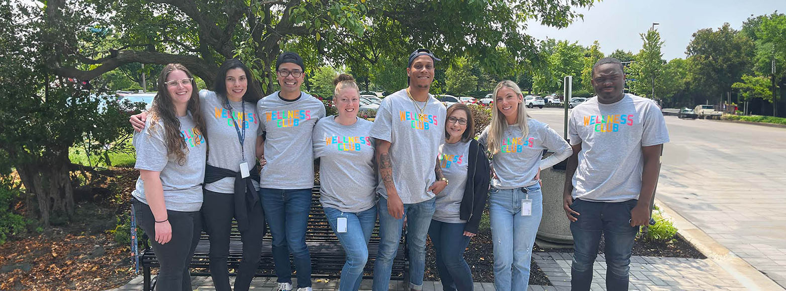 RetireeFirst staff standing side-by-side wearing "Wellness Club" t-shirts