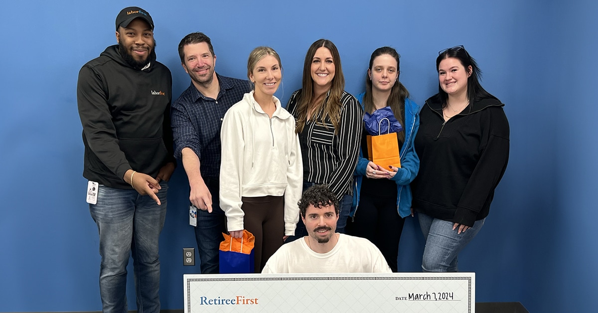 Retiree First team member group photo holding a giant check