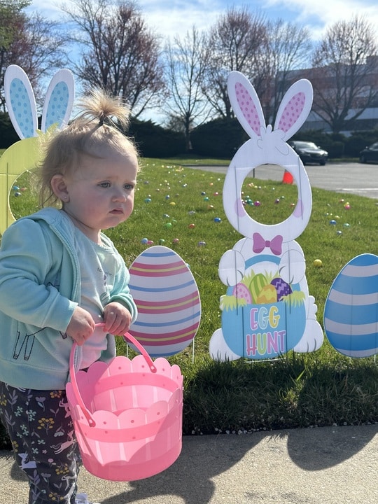 toddler holding her pink easter egg basket at an easter event